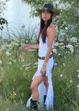 Vestido largo blanco de corte recto con escote strapless y falda con volados en el ruedo que aportan transparencia y movimiento.