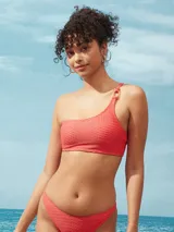 Bikini de una pieza con diseño de un solo hombro, confeccionada en tela texturizada color salmón. Presenta un detalle de argolla decorativa en el hombro y copas removibles.