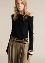 Mono de diseño combinado con cuerpo de remera negra de escote asimétrico y manga larga, unido a un pantalón de vestir color beige de corte recto con bolsillos laterales y cinturón doble integrado.