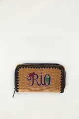 Billetera rectangular color marrón con textura tejida, cierre perimetral con cremallera y bordes decorados con costura en zigzag negra. Cuenta con el texto bordado 'Rio' en tonos violeta y verde con una palmera y un tucán integrados.