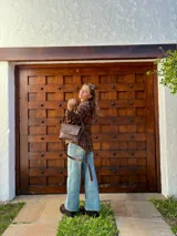 Cartera bandolera de cuero color chocolate con solapa frontal, costuras a la vista y herrajes metálicos. Incluye dos correas desmontables, una corta y una larga, y cuenta con bolsillo interior.