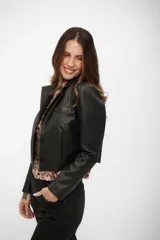 Campera corta de cuero sintético en color negro, con cuello solapa, cierre frontal de botones y mangas largas.