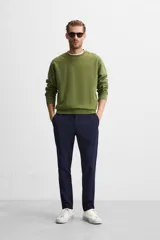 Pantalón de corte slim fit confeccionado en tejido elástico, con cintura elástica, cierre frontal con cremallera y botón, bolsillos laterales y bolsillos traseros de vivo.