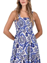 Vestido largo de corte holgado con estampado floral en tonos azul y blanco. Presenta escote cuadrado, cuerpo con frunces elásticos y falda con volados escalonados.