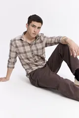 Camisa de manga larga confeccionada en viyela de algodón con diseño de cuadros en tonos beige y marrón. Presenta cierre frontal con botones, cuello clásico y bolsillo en el pecho.