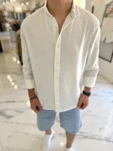 Camisa oversize de lino color blanco, con cuello mao, manga larga y cierre frontal de botones.
