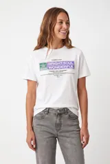Remera blanca con cuello redondo, manga corta y diseño estampado en el frente con rectángulos en tonos violeta y verde con inscripciones.