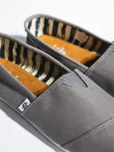 Alpargata de lona negra con suela de goma blanca flexible. Presenta una etiqueta pequeña con el logo de la marca en el lateral y plantilla interior de símil cuero.