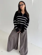 Sweater estilo chomba con cierre frontal, confeccionado en tejido bremer rayado de manga larga. Presenta un diseño amplio y moderno con cuello polo.