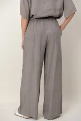 Pantalón palazzo de lino color blanco, con cintura elástica fruncida, bolsillos laterales y detalle de alforzas verticales en los laterales.