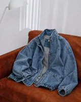 Campera de jean con diseño de monograma grabado, cuello alto, cierre frontal y puños elásticos. Presenta bolsillos frontales con solapa y botones metálicos.