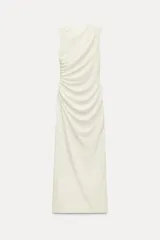 Vestido midi color blanco hueso, con cuello subido, manga sisa y detalle de drapeado en el delantero. Cierre en la espalda con cremallera oculta.