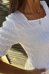 Remera negra de algodón con textura fruncida en todo el cuerpo y mangas cortas con terminación de volado.