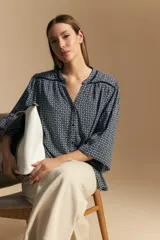 Camisa de manga larga con silueta relajada, estampado a rayas verticales en blanco y gris, escote abierto con botones frontales y puños elastizados.