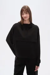 Buzo negro de corte holgado con capucha, manga larga y bolsillo frontal tipo canguro. Presenta un diseño minimalista con una solapa frontal sobre el pecho.