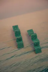 Par de aros colgantes con forma geométrica irregular, recubiertos de strass negros sobre base plateada.