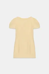 Vestido corto color amarillo claro, con cuello barco, mangas cortas abullonadas y pliegues en la parte delantera. Presenta falsos bolsillos de vivo y costuras marcadas. Cierre en la espalda con cremallera oculta.