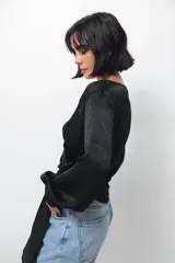 Camisa tipo blusa cruzada de seda negra, con escote en V profundo, mangas largas con puños abotonados y lazo lateral para anudar en la cintura.