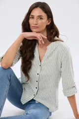 Camisa rayada de lino y algodón, con diseño de rayas verticales en color verde y blanco, manga larga y cuello mao con escote en V. Cuenta con cierre frontal de botones.