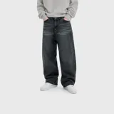 Pantalón de jean con corte ultra baggy, color negro con efecto lavado. Presenta un diseño de tiro medio, cinco bolsillos y cierre frontal con botón y cremallera.