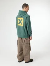 Hoodie verde con capucha y bolsillo canguro frontal. Presenta un gran estampado en la espalda que consiste en un cuadrado amarillo con una cruz verde en el centro.