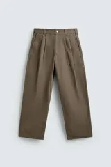 Pantalón de corte baggy fit confeccionado en tejido de algodón con estructura diagonal y efecto lavado. Presenta cintura con pliegues frontales, bolsillos laterales, bolsillos traseros de vivo y un bolsillo lateral adicional con doble vivo en la pernera. Cierre frontal con cremallera y botón.