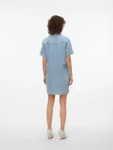 Vestido corto de denim en tono celeste claro, con cuello camisero, cierre frontal con botones metálicos, bolsillos con solapa en el pecho y mangas cortas con vuelta.