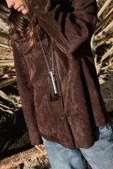 Sobrecamisa de tejido efecto ante en color marrón, con cuello solapa, manga larga con puños y cierre frontal de botones. Presenta un bolsillo de plastrón en el pecho.