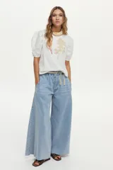 Jean wide leg color celeste, con cintura elástica ajustable mediante cordón y detalles de flecos en el ruedo.