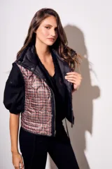 Chaleco negro con cierre frontal y cuello alto, de corte al cuerpo y diseño acolchado. Reversible, con interior a cuadros.