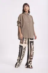 Camisa blanca de manga larga con textura, cuello clásico y botones frontales.