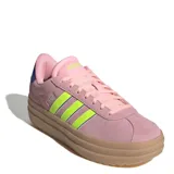 Championes Adidas modelo VL Court Bold de plataforma, con capellada de gamuza en tono rosado. Presenta las icónicas tres tiras laterales en color verde neón con bordes oscuros, cordones al tono y suela de plataforma de goma en color marrón claro.