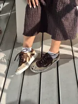 Zapatillas bajas de cuero vacuno color beige con apliques de cuero marrón y estampado animal print.