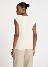 Musculosa color crema de algodón con cuello redondo y tirantes anchos. Presenta una banda fruncida en el frente con detalle de argolla metálica lateral.