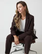 Blazer sastrero entallado color beige, con cuello de solapa, cierre frontal con un botón a tono y hombreras estructuradas. Presenta bolsillos laterales con solapa y forro interno.