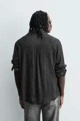 Camisa de corte relajado con diseño de cuadros en tonos negro y beige, cuello camisero, manga larga y cierre frontal de botones.