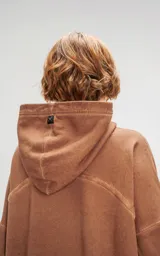 Hoodie oversize color beige con efecto batik, costuras expuestas y recortes estructurales. Presenta capucha amplia y bolsillo frontal tipo canguro.