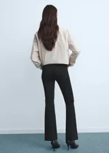 Pantalón de jean negro de tiro medio y corte flare, con diseño crop y bajo deshilachado. Cuenta con cierre de cremallera, botón frontal, trabillas para cinturón y cinco bolsillos clásicos.