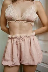 Shorts de tiro bajo en mezcla de viscosa y lino, color rosado con sutiles rayas verticales. Presenta cintura elástica fruncida con lazada frontal ajustable y aplicación de puntilla en contraste en el borde superior. Diseño de bajo abullonado tipo globo.
