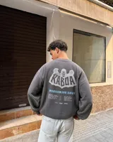 Buzo gris oscuro con efecto acid wash, corte regular fit y cuello redondo. Presenta una estampa grande en la espalda con diseño de calavera, el texto "Kaboa" y detalles de fechas de tour en tonos claros.