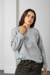 Buzo de punto color blanco, de corte oversize y cuello redondo, decorado con flores aplicadas en relieve con centros bordados en perlas.