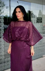 Vestido largo de fiesta color gris, confeccionado en tejido con textura calada tipo red. Presenta un diseño de silueta fluida con mangas amplias tipo murciélago y escote redondo.