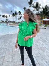 Camisa verde brillante de muselina con volados en el frente y tachas plateadas.