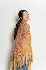 Chaleco tejido a crochet con flecos largos, diseño multicolor con predominancia de tonos tierra, naranja, amarillo y rosa.