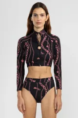 Crop top de bikini negro con estampado de cadenas rosadas, cierre frontal con tirador de flor, cuello alto y mangas largas.