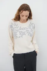 Buzo de tejido de punto en color beige, con cuello redondo y mangas largas. Presenta un delicado bordado de ramas y hojas en color crema en la parte superior del frente.