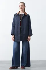 Trench tipo barn jacket color marrón, con cuello camisero en contraste azul marino, cierre frontal con broches y bolsillos amplios. De silueta recta y calce cómodo.