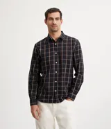 Camisa de hombre de manga larga, confeccionada en franela ligera con estampado cuadrillé en tonos oscuros y líneas finas blancas y naranjas. Cuenta con cuello clásico y abotonado frontal.