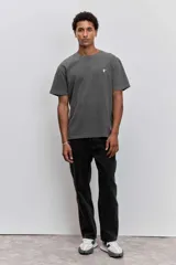 Remera de algodón color marrón con efecto lavado, de corte clásico y cuello redondo. Presenta un pequeño bordado de un pájaro en el pecho.