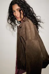 Chaqueta de efecto ante color marrón claro, con cuello solapa, manga larga con trabillas en los hombros y bajo abullonado. Cierre frontal con cremallera y botones ocultos por solapa.